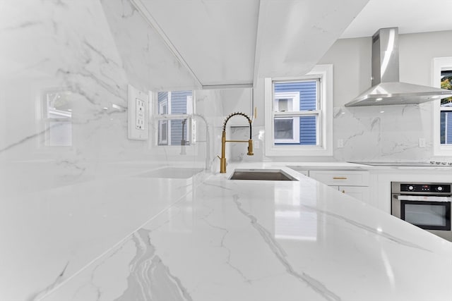 kitchen featuring sink, wall chimney exhaust hood, white cabinets, stainless steel oven, and black electric stovetop