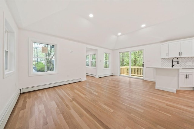 unfurnished living room with light wood finished floors, baseboard heating, recessed lighting, and vaulted ceiling