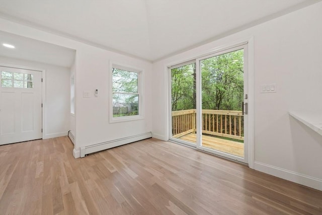 doorway with baseboards, baseboard heating, light wood-style flooring, and a baseboard heating unit