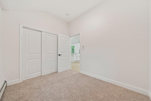unfurnished bedroom with carpet, a closet, baseboards, and lofted ceiling