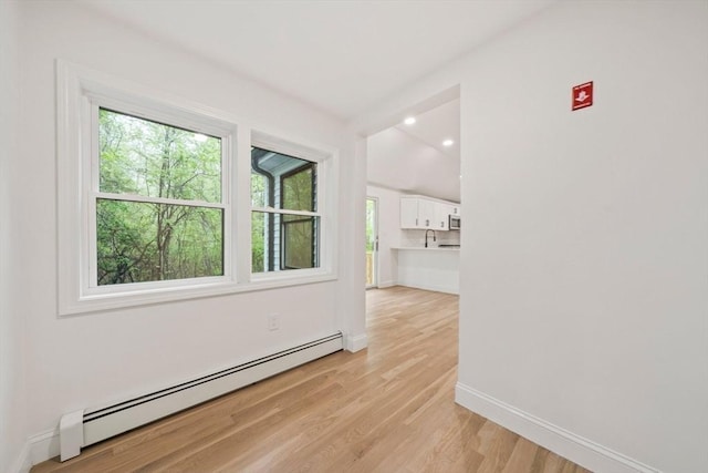 spare room with a wealth of natural light, baseboards, a baseboard radiator, and light wood-style floors