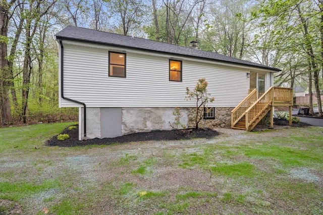 rear view of house with a lawn, a chimney, a wooden deck, and stairs