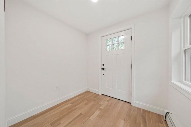 entryway with a baseboard heating unit, baseboards, and light wood-type flooring