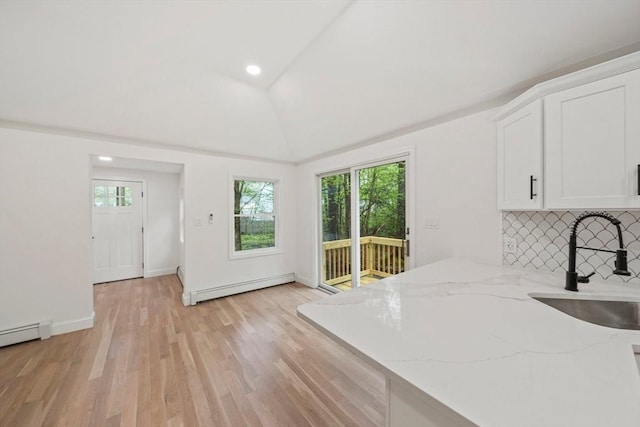 kitchen featuring a healthy amount of sunlight, light stone countertops, baseboard heating, and white cabinets