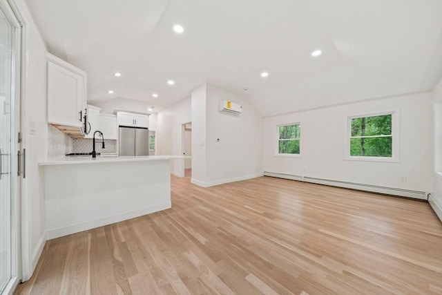 unfurnished living room featuring light wood-type flooring, baseboards, lofted ceiling, and a wall unit AC