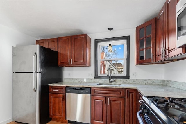 kitchen featuring light stone countertops, appliances with stainless steel finishes, sink, decorative light fixtures, and light hardwood / wood-style floors