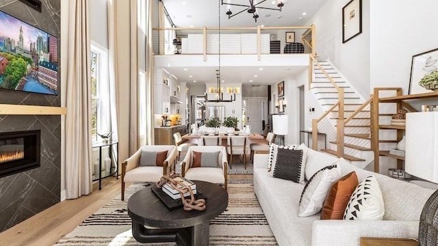 82 Kestrel Hts Unit 41, Plymouth, MA 02360 - living area featuring a chandelier, a towering ceiling, light wood-style floors, stairway, and a premium fireplace