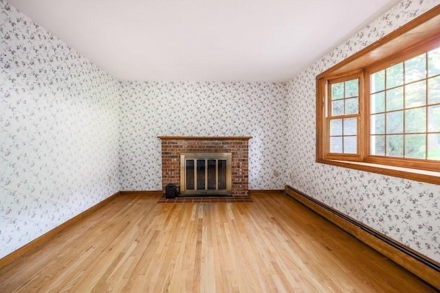 unfurnished living room featuring a fireplace, wood-type flooring, and baseboard heating