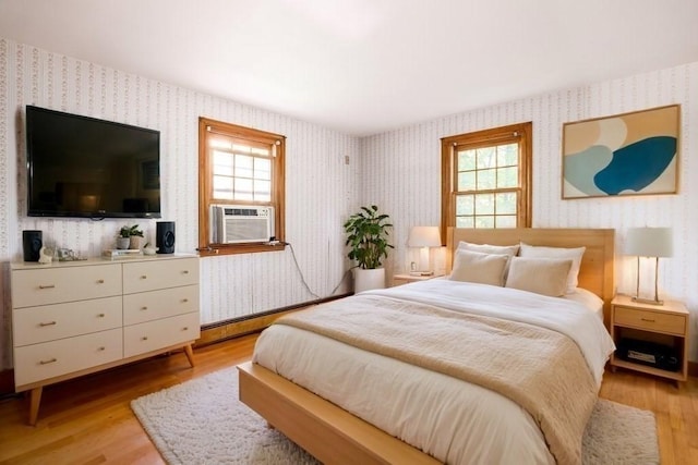 bedroom featuring multiple windows, light hardwood / wood-style flooring, and cooling unit