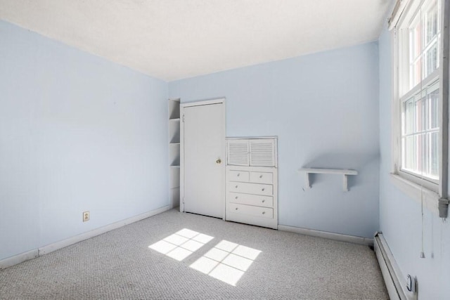 unfurnished bedroom with light carpet and a baseboard heating unit