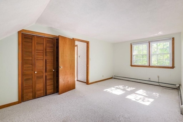 unfurnished bedroom featuring light carpet, vaulted ceiling, and a baseboard heating unit