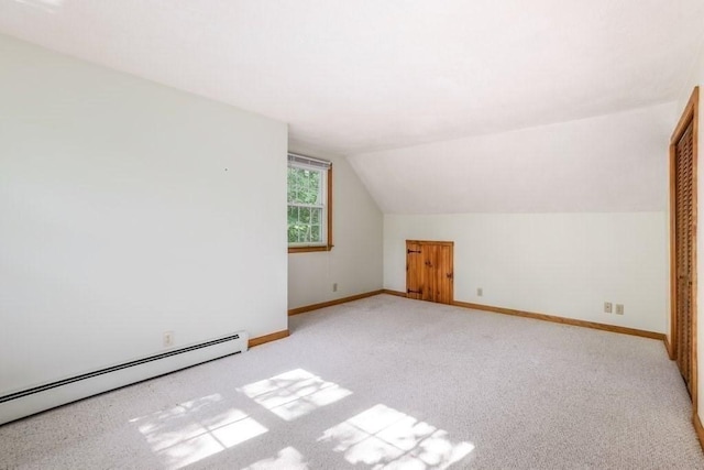 additional living space featuring light carpet, vaulted ceiling, and a baseboard heating unit