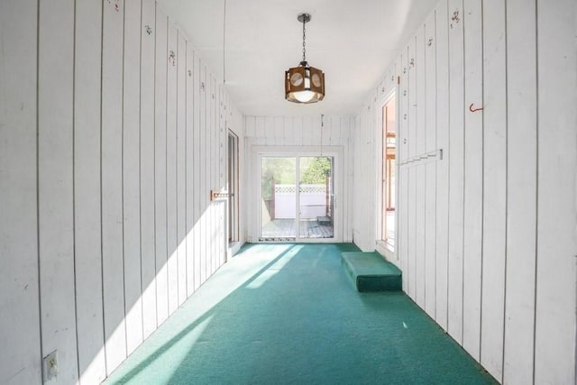 hallway featuring carpet flooring and wooden walls