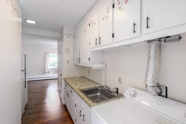 laundry room with sink, cabinets, baseboard heating, dark hardwood / wood-style flooring, and washer / clothes dryer