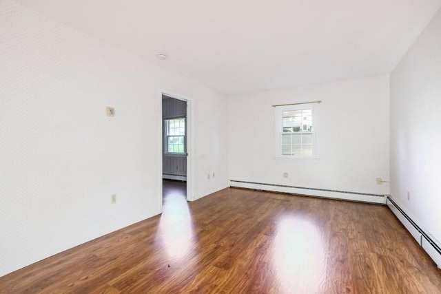 empty room featuring baseboard heating and hardwood / wood-style floors