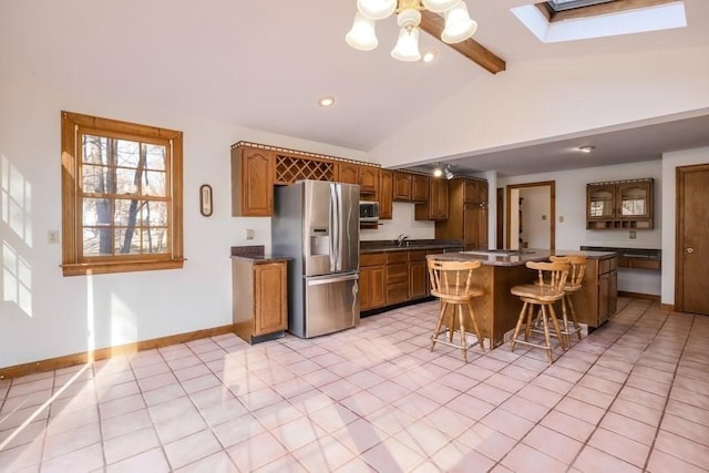 kitchen featuring a kitchen bar, a skylight, stainless steel appliances, beamed ceiling, and a center island