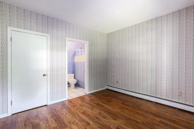 unfurnished bedroom featuring baseboard heating, ensuite bath, and light hardwood / wood-style floors