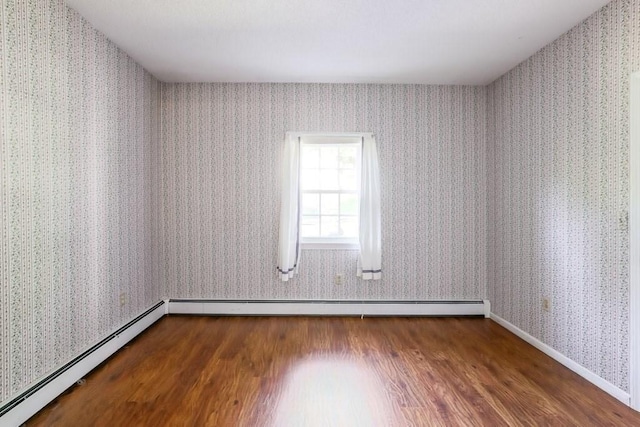 empty room featuring baseboard heating and hardwood / wood-style floors