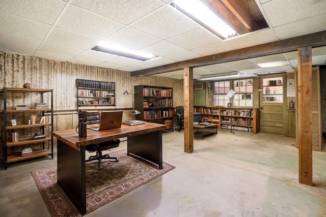 office area with a paneled ceiling and concrete flooring