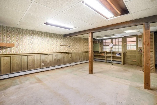 basement with baseboard heating and a drop ceiling