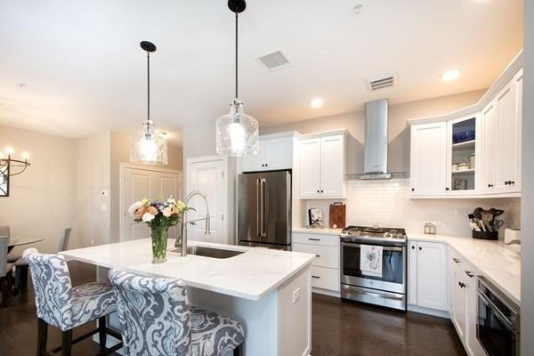 kitchen featuring a sink, visible vents, light countertops, appliances with stainless steel finishes, and wall chimney range hood