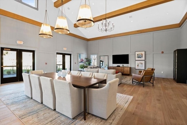 dining room featuring a wealth of natural light, french doors, a decorative wall, and light wood-style flooring