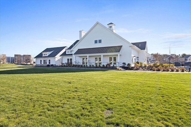 back of property featuring metal roof, a yard, and a standing seam roof