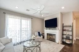 living area with a ceiling fan, recessed lighting, a fireplace, and dark wood-style floors