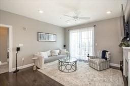 living room with ceiling fan, a fireplace, wood finished floors, and baseboards