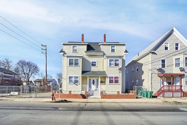 view of front facade with a residential view, fence, and a chimney