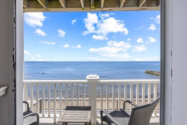 balcony featuring a view of the beach and a water view