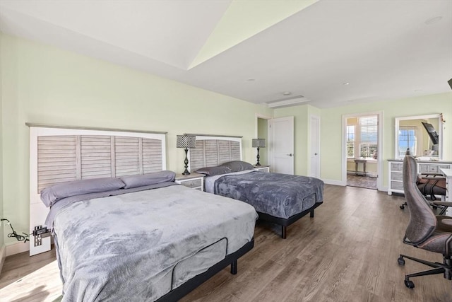 bedroom with baseboards, lofted ceiling, and wood finished floors