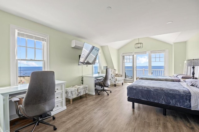 bedroom with vaulted ceiling, wood finished floors, and a wall mounted air conditioner
