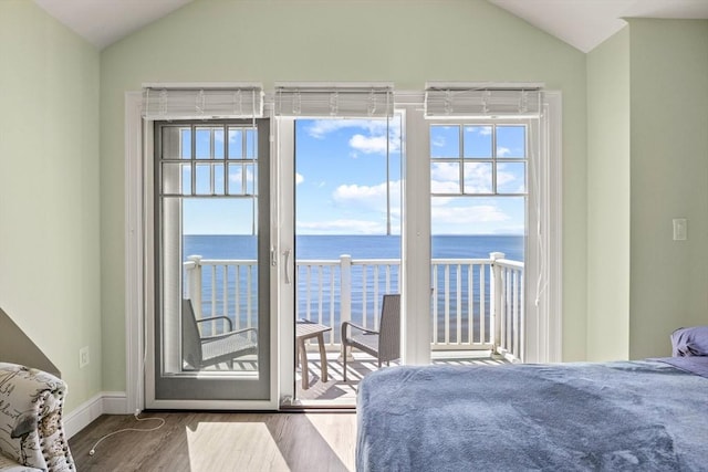 bedroom featuring a water view, access to outside, vaulted ceiling, and wood finished floors