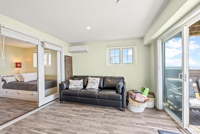 living area with wood finish floors, an AC wall unit, a healthy amount of sunlight, and recessed lighting