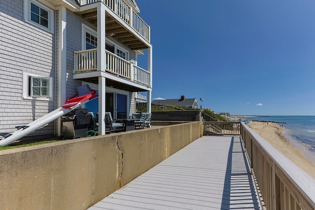 view of dock with a balcony and a water view