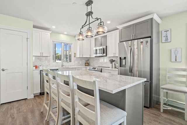 kitchen featuring backsplash, appliances with stainless steel finishes, light stone counters, and wood finished floors