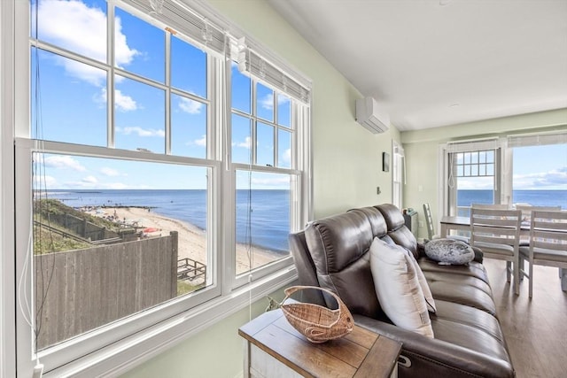 living area featuring a wall unit AC, a water view, and a view of the beach