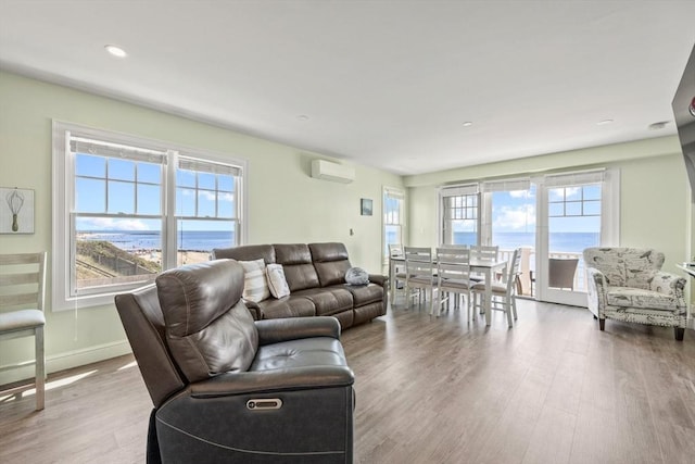living area with baseboards, recessed lighting, wood finished floors, and an AC wall unit