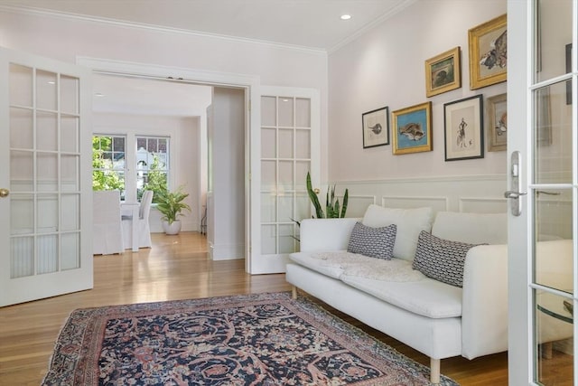 living area featuring hardwood / wood-style flooring, crown molding, and french doors