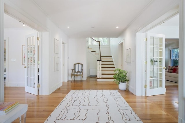 corridor with french doors, light wood-type flooring, and ornamental molding