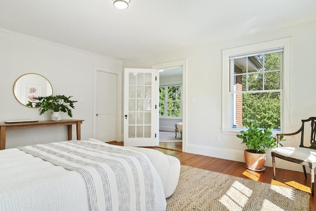 bedroom with multiple windows, crown molding, and hardwood / wood-style flooring