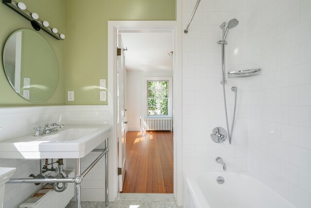 bathroom with sink, tiled shower / bath, and radiator