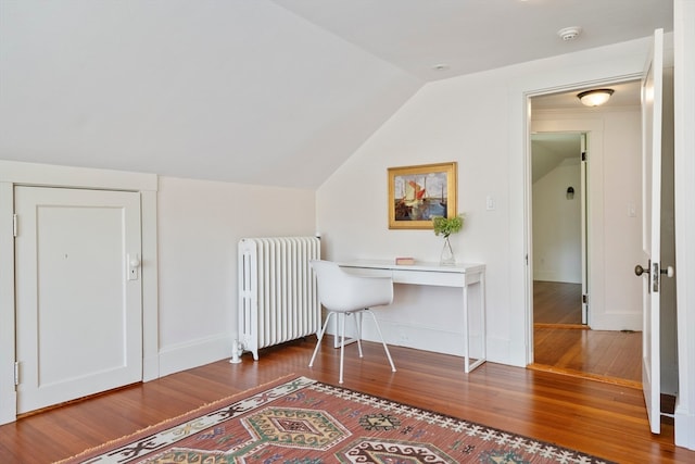 additional living space featuring radiator heating unit, dark hardwood / wood-style flooring, and vaulted ceiling