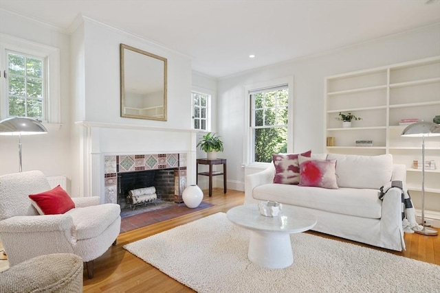 living room with a tiled fireplace, plenty of natural light, and hardwood / wood-style flooring