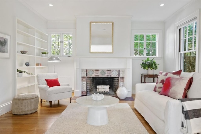 sitting room featuring wood-type flooring, crown molding, and a tiled fireplace