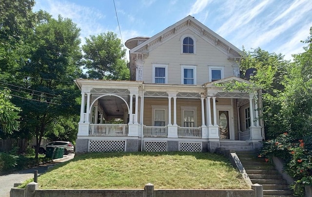 italianate home featuring covered porch and a front lawn