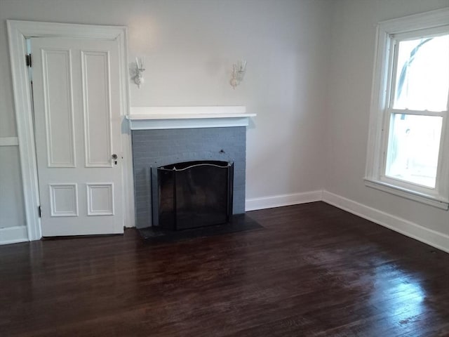 unfurnished living room featuring plenty of natural light, a fireplace, and dark wood-style flooring