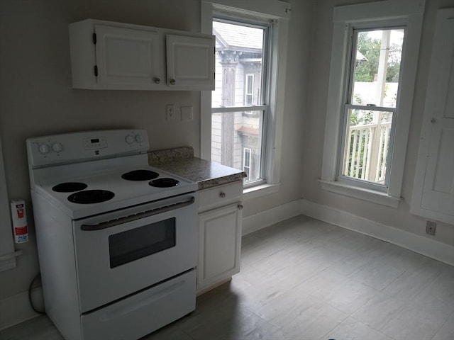 kitchen featuring baseboards, white cabinetry, and white range with electric cooktop