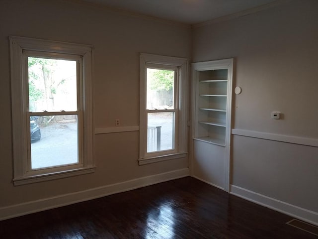 unfurnished room with dark wood finished floors, visible vents, baseboards, and ornamental molding